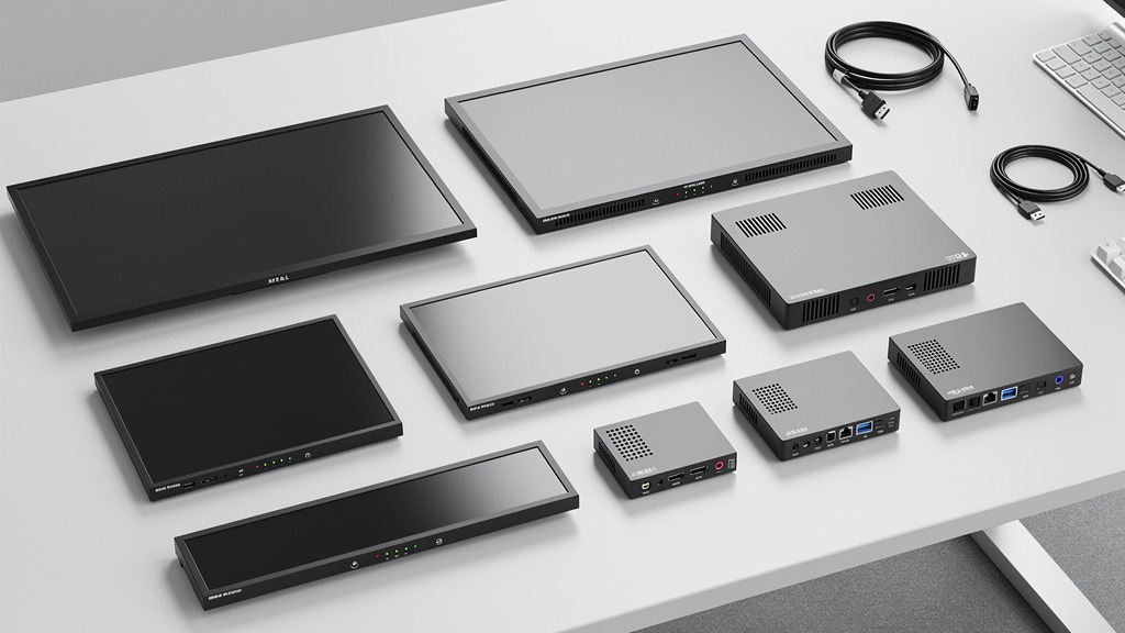 An array of digital signage displays of different sizes and media players laid out on a light-colored surface.